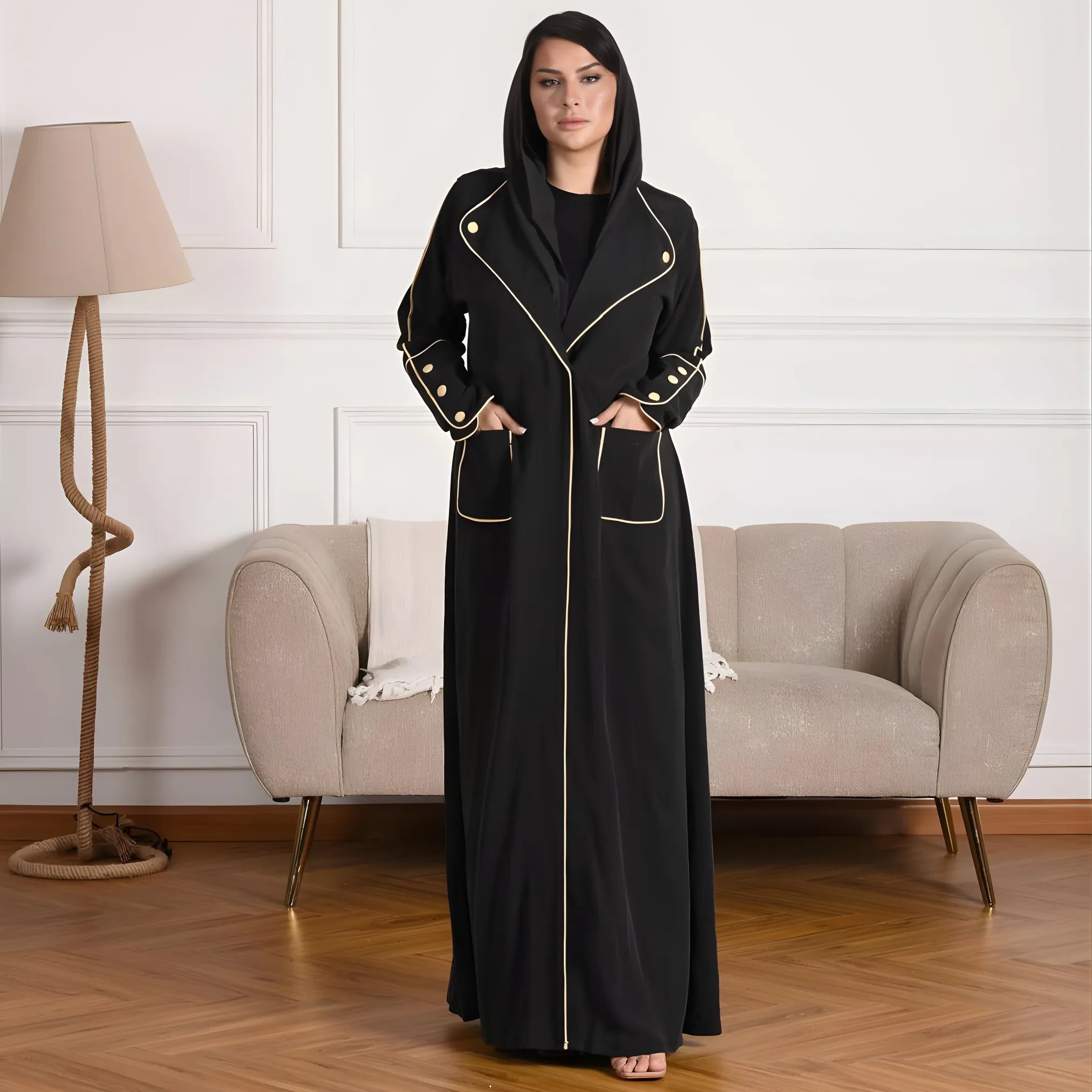 Woman wearing a black abaya with gold accents in a living room setting.