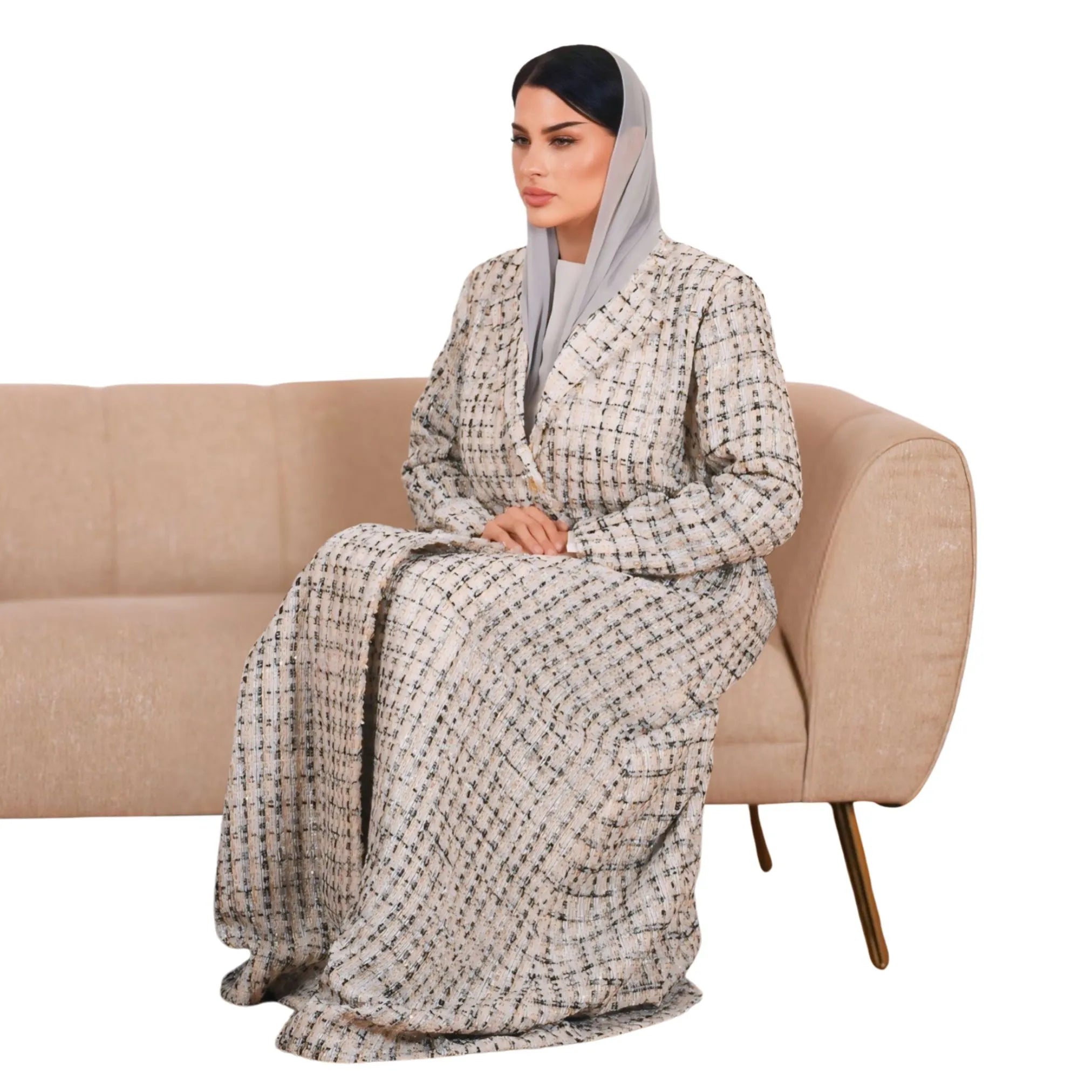 Woman sitting on a beige couch wearing a patterned robe with a plain background