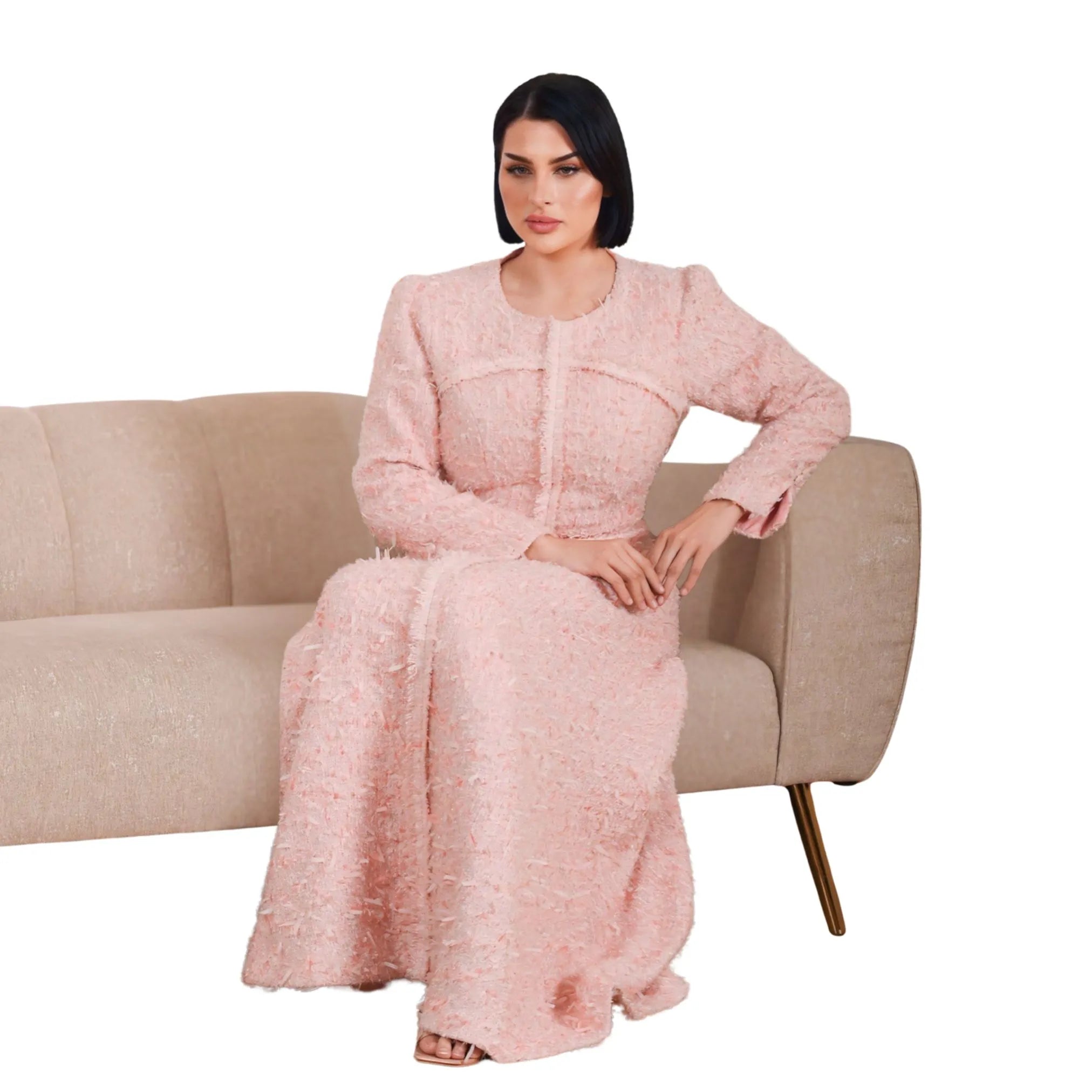 Woman in a pink dress sitting on a beige sofa against a white background
