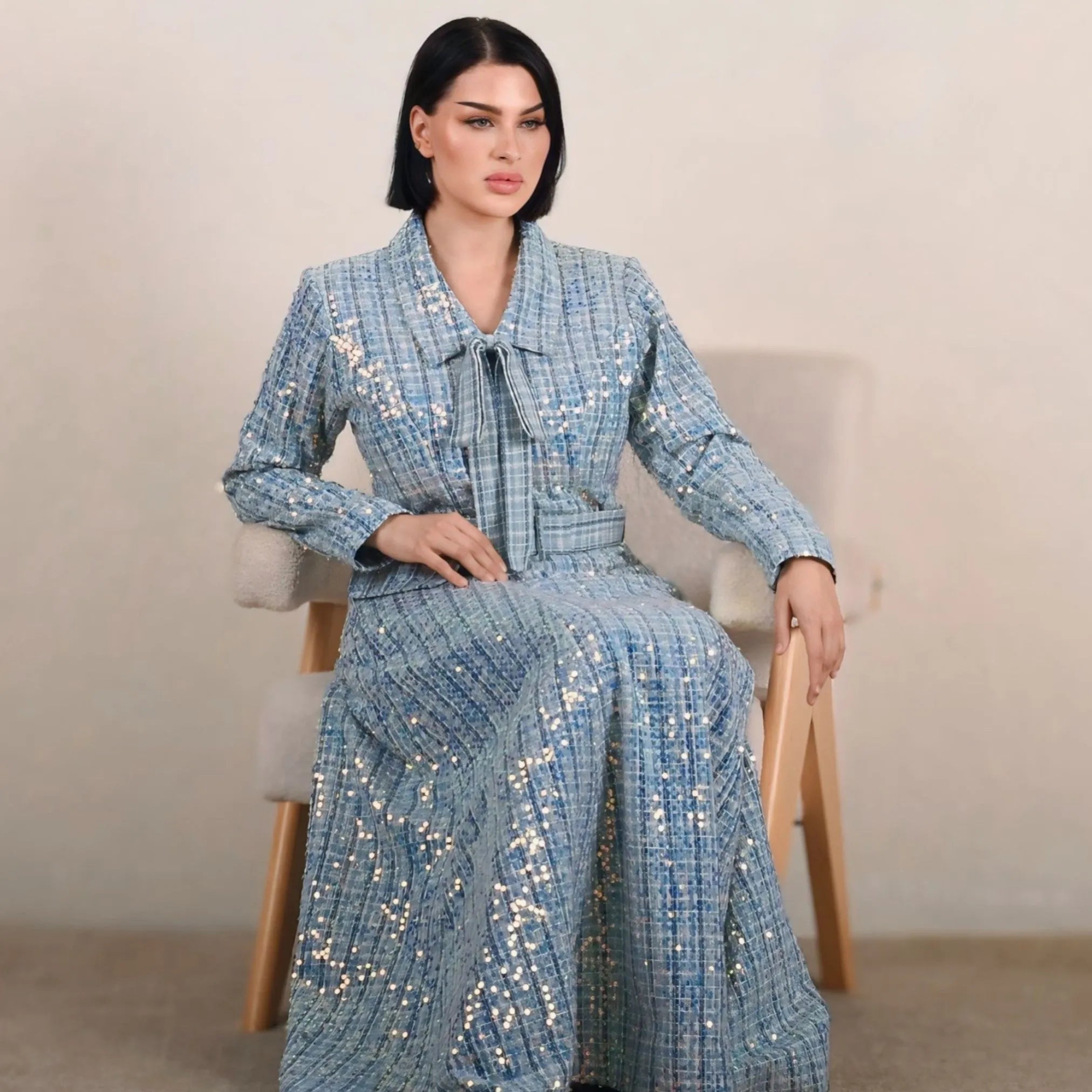 Woman wearing a blue patterned outfit sitting on a chair.