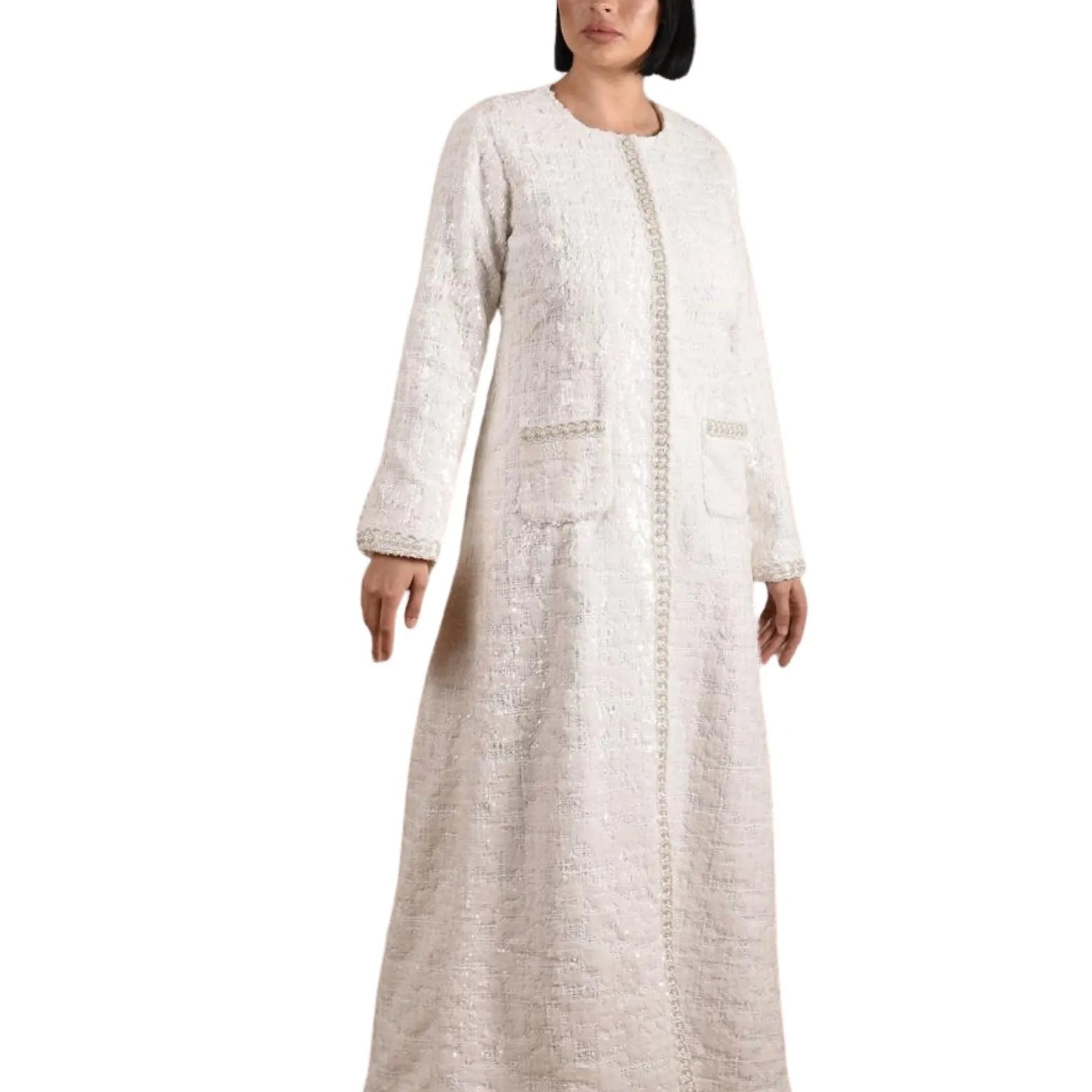 Woman wearing a long, light-colored dress with a textured pattern on a white background