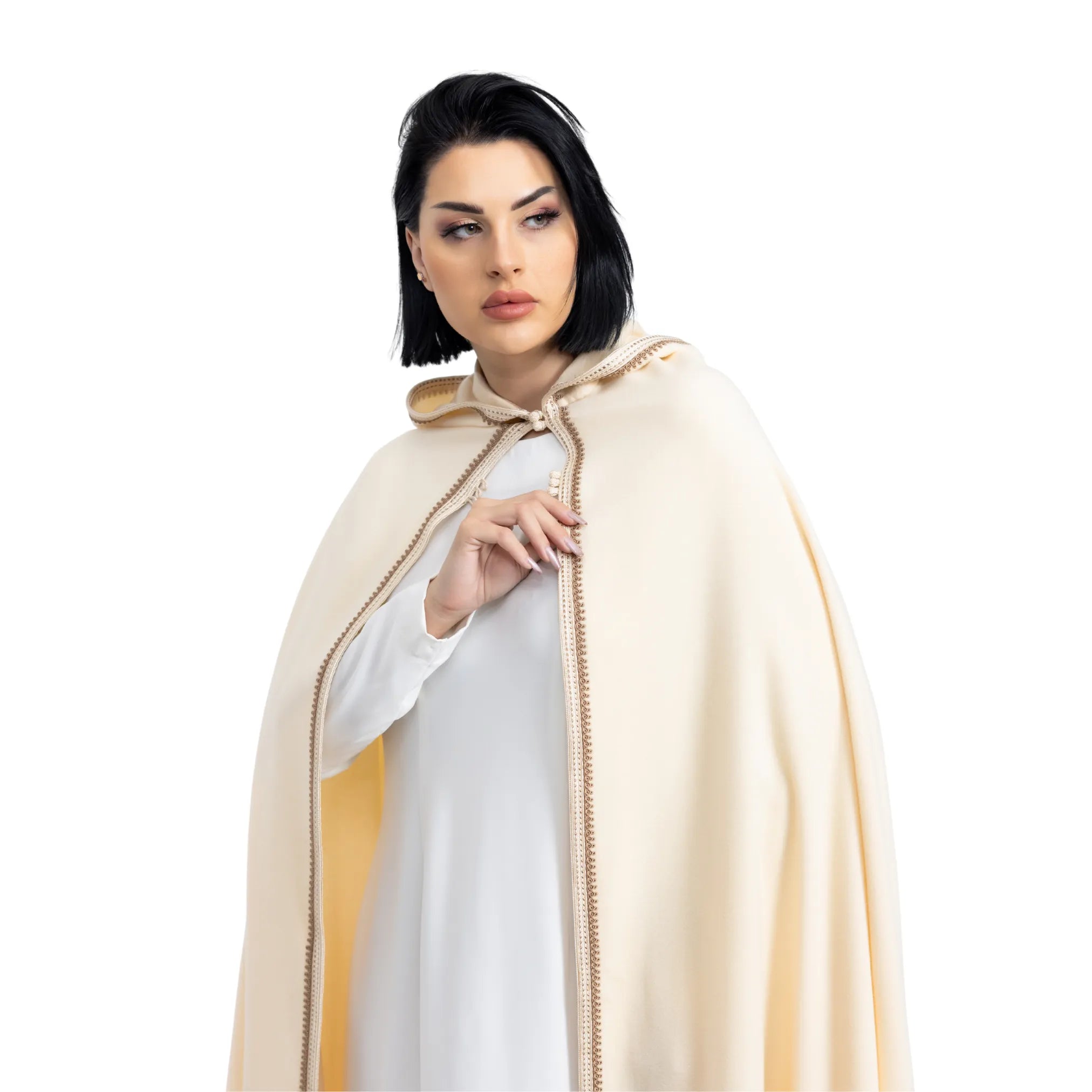 Woman wearing a beige cape over a white dress on a white background