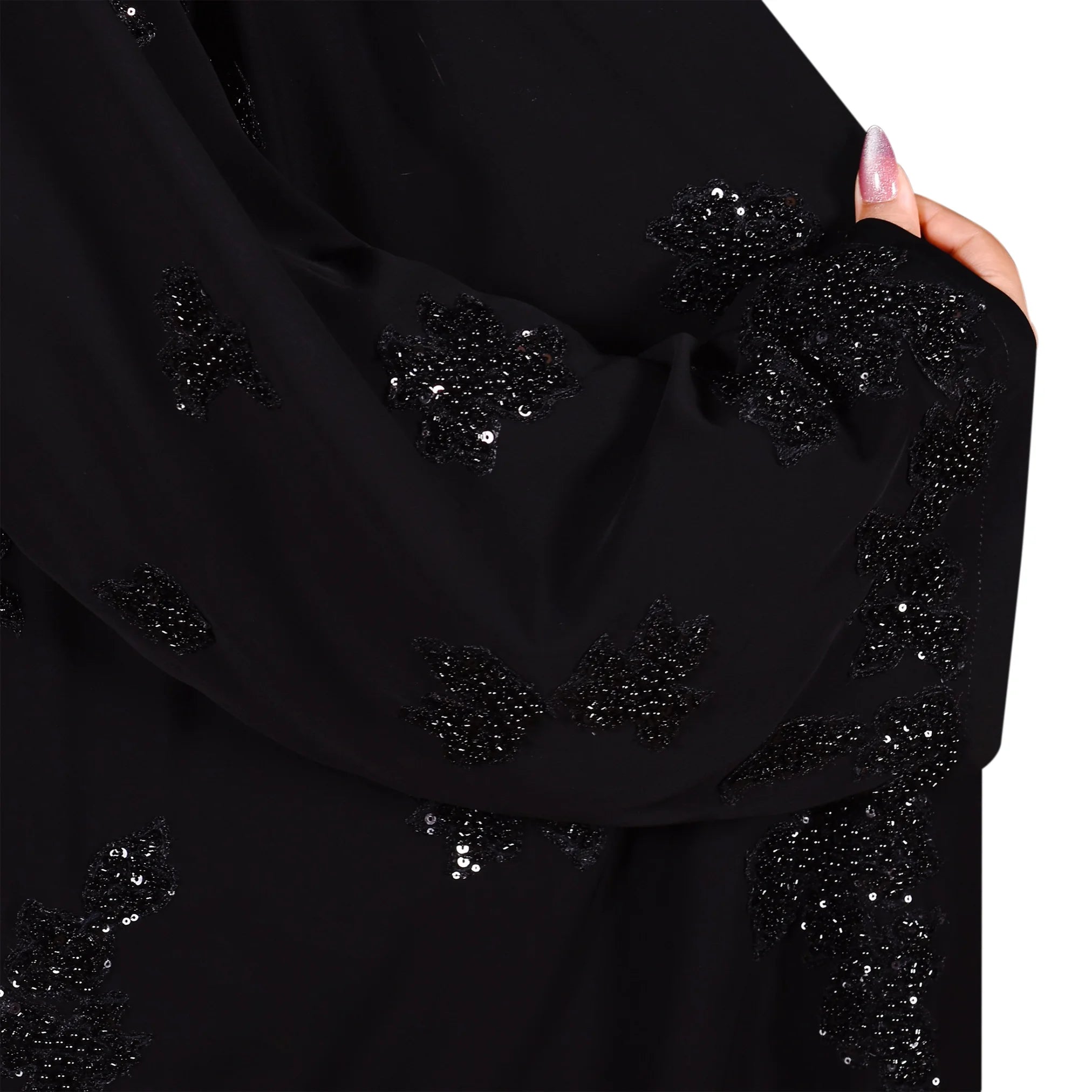 Black garment with sequin embellishments held by a hand on a white background
