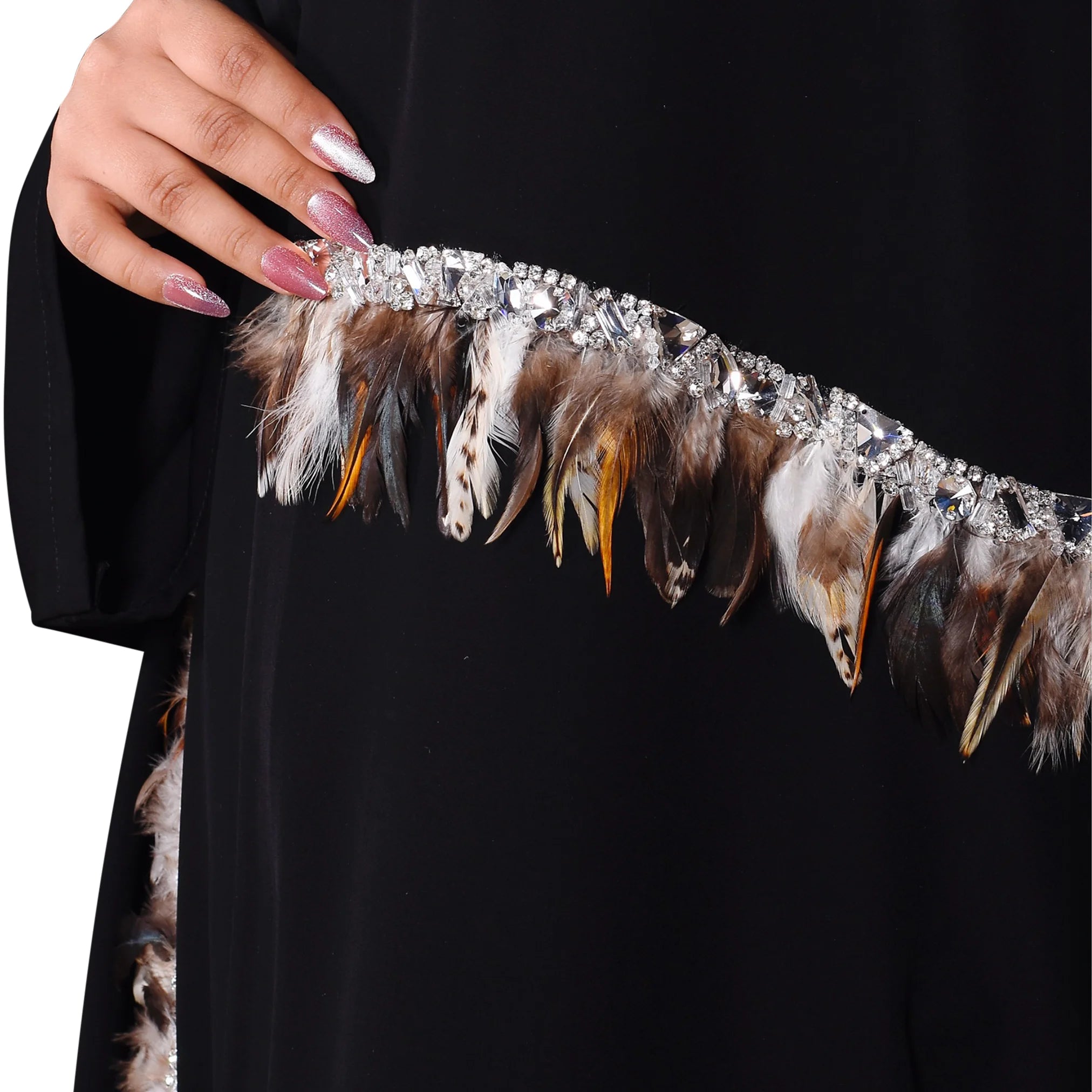 Feathered headband with rhinestones held by a hand against a black background