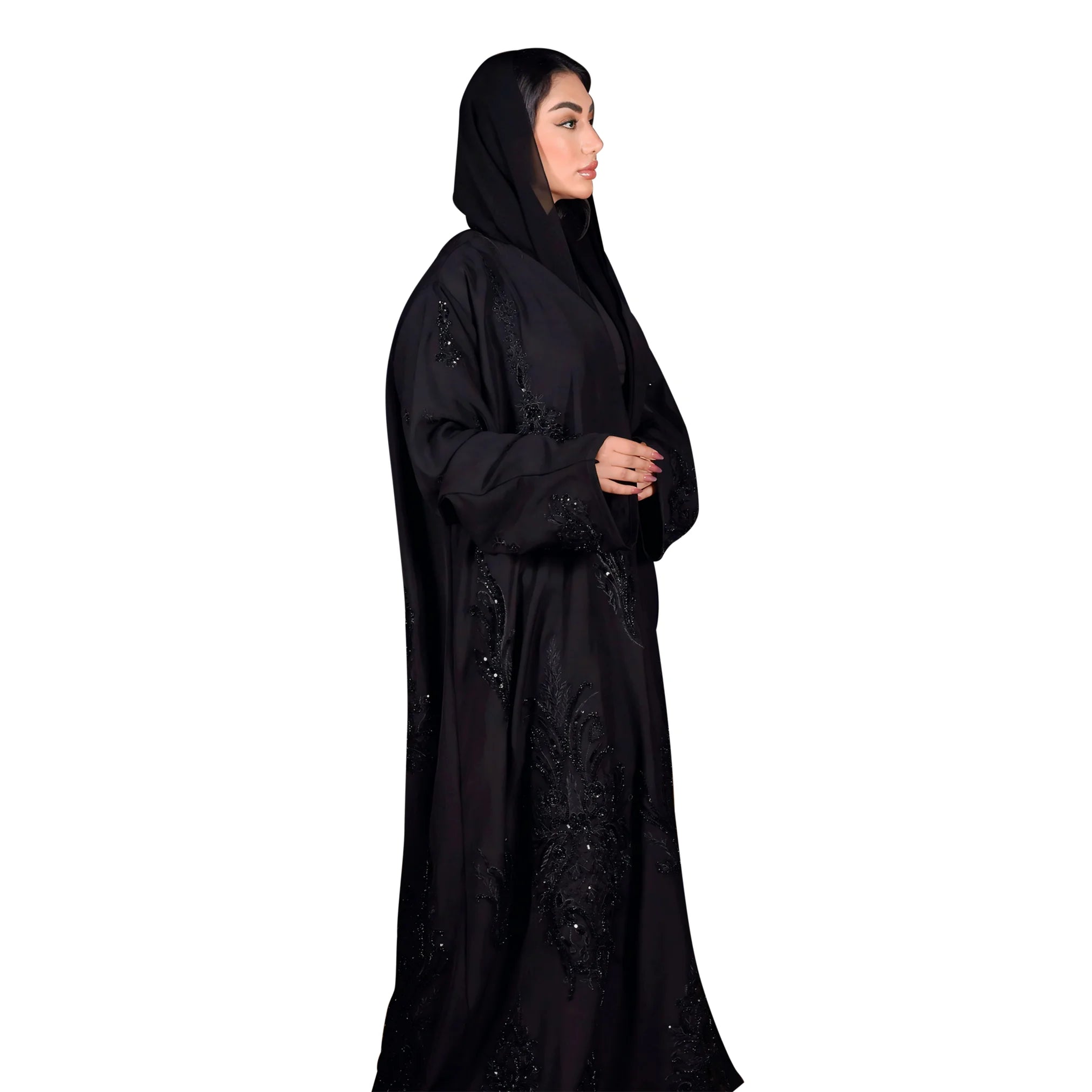 Woman wearing a black abaya with intricate designs on a white background