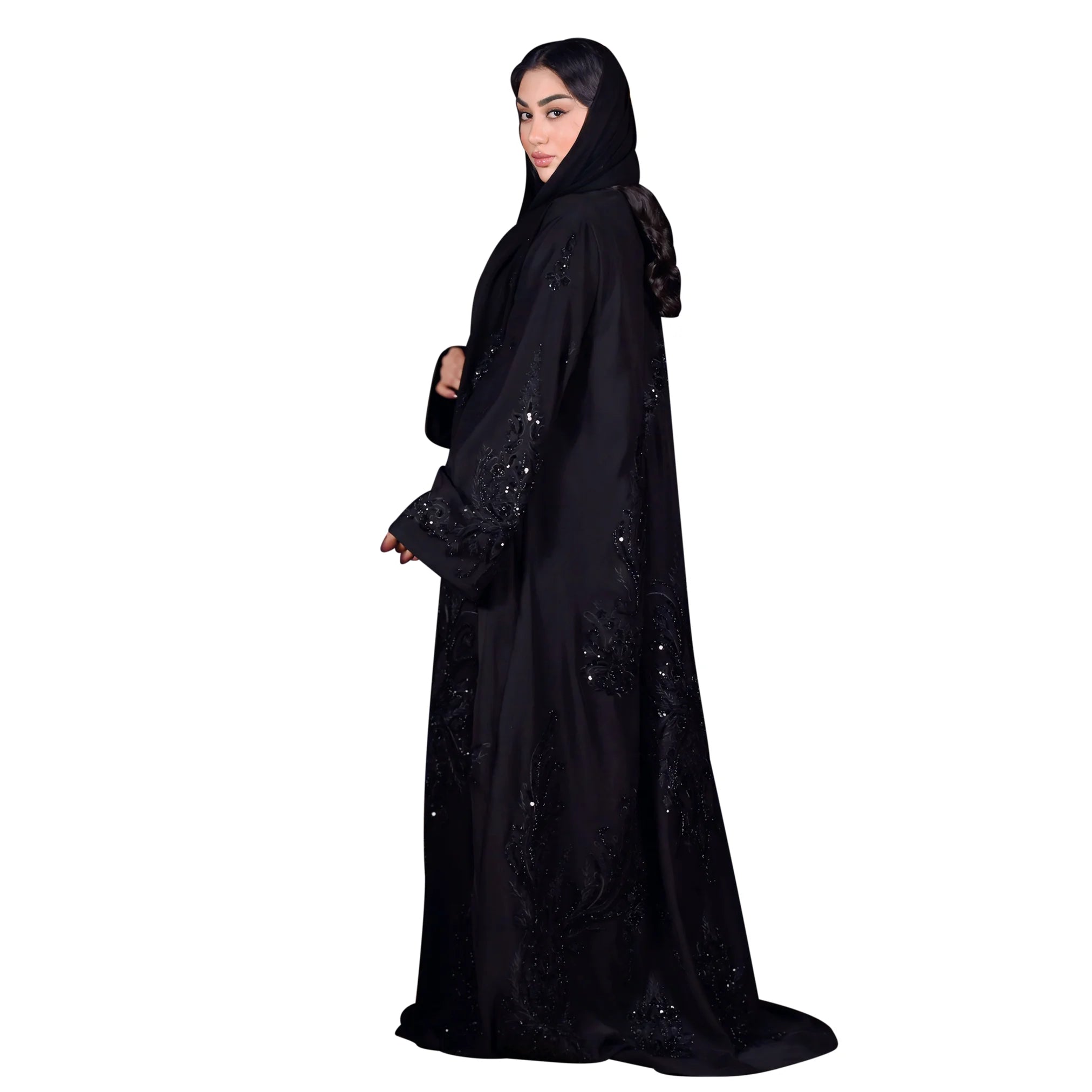 Woman wearing a black abaya with intricate designs on a white background