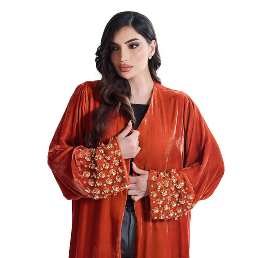 Woman wearing a red velvet abaya with gold embroidery on a white background