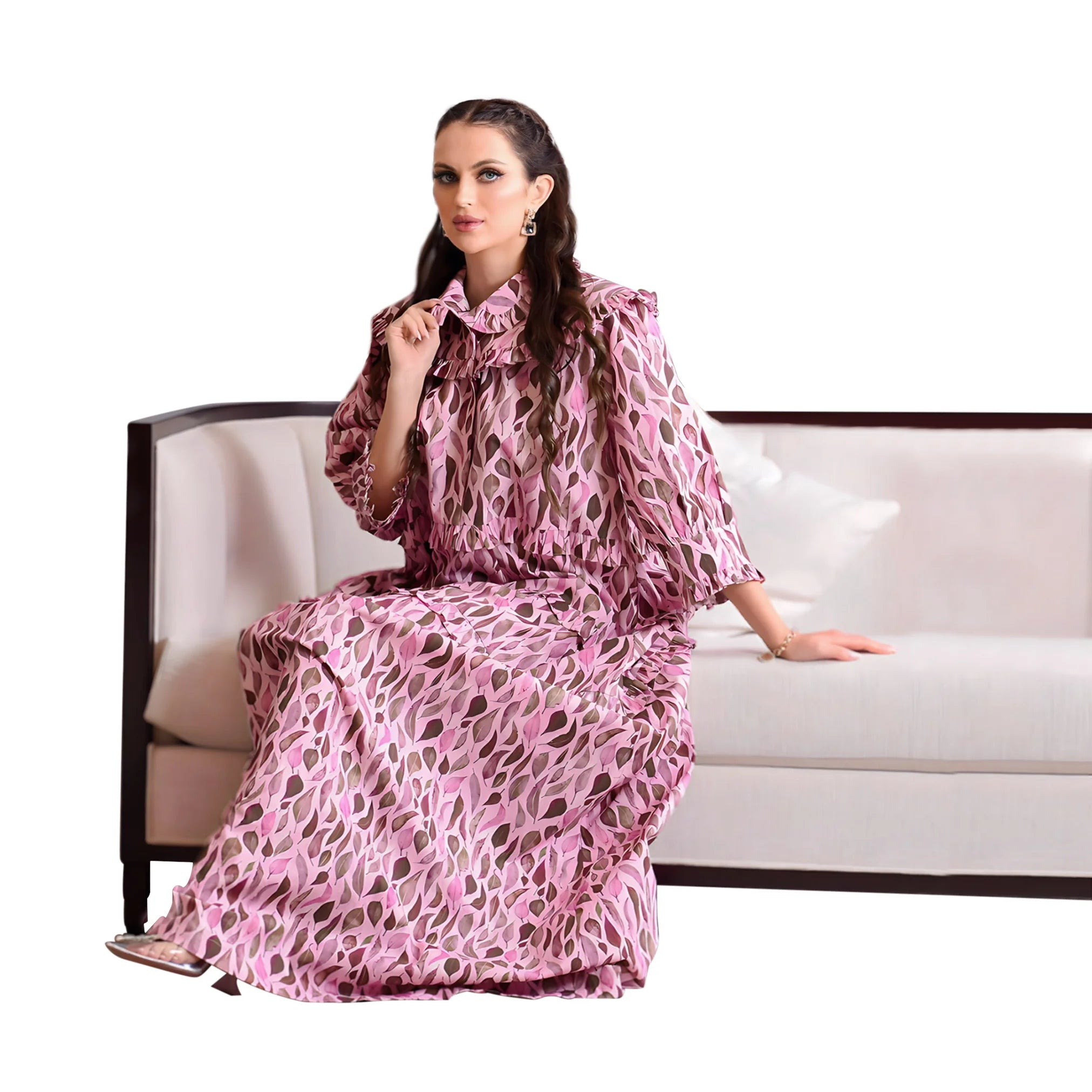 Woman in a pink patterned dress sitting on a white couch with a white background