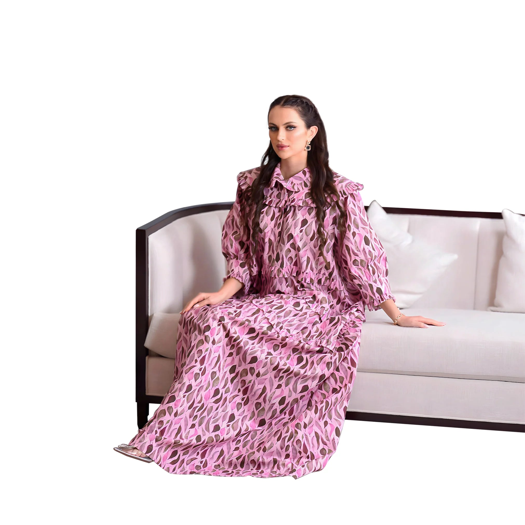 Woman in a pink leopard print dress sitting on a white couch with a white background