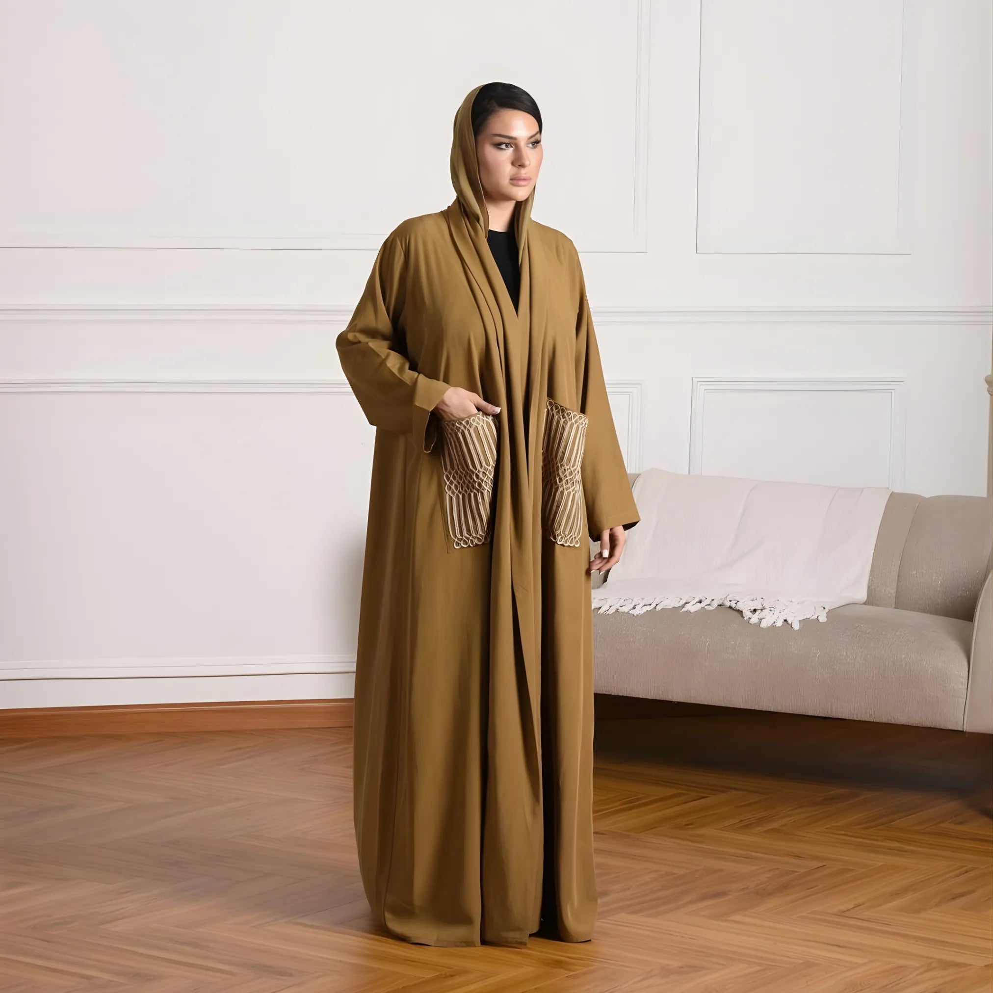 Woman wearing a long, olive green abaya in a living room setting.