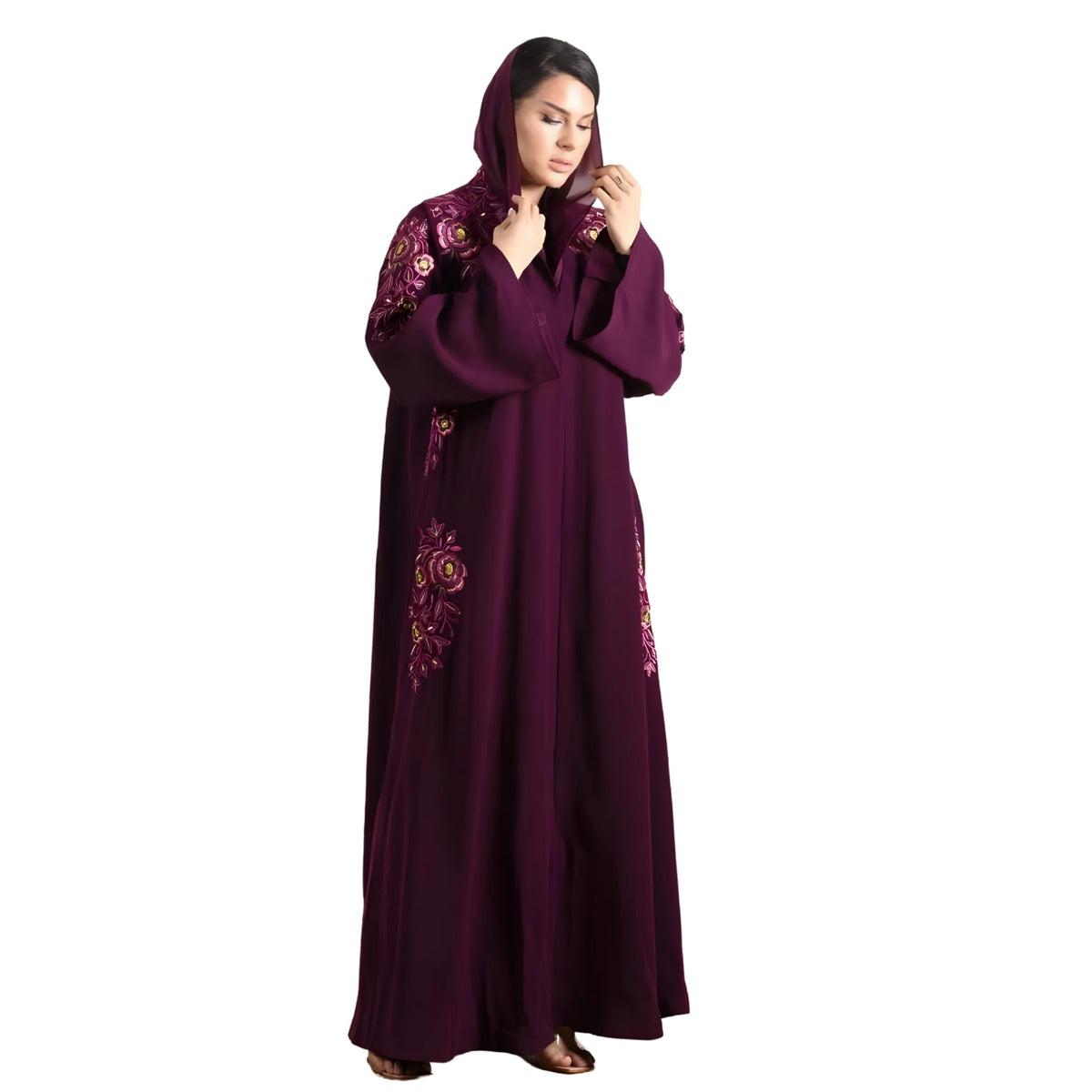 Woman wearing a long, dark purple Abaya with floral embroidery on a white background