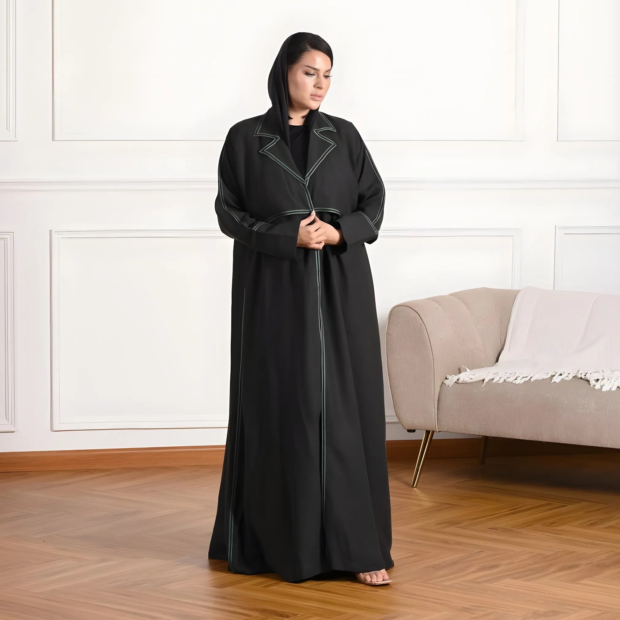 Woman wearing a black abaya in a room with a beige sofa.