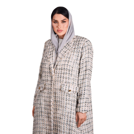 Woman wearing a patterned coat and gray hijab on a white background