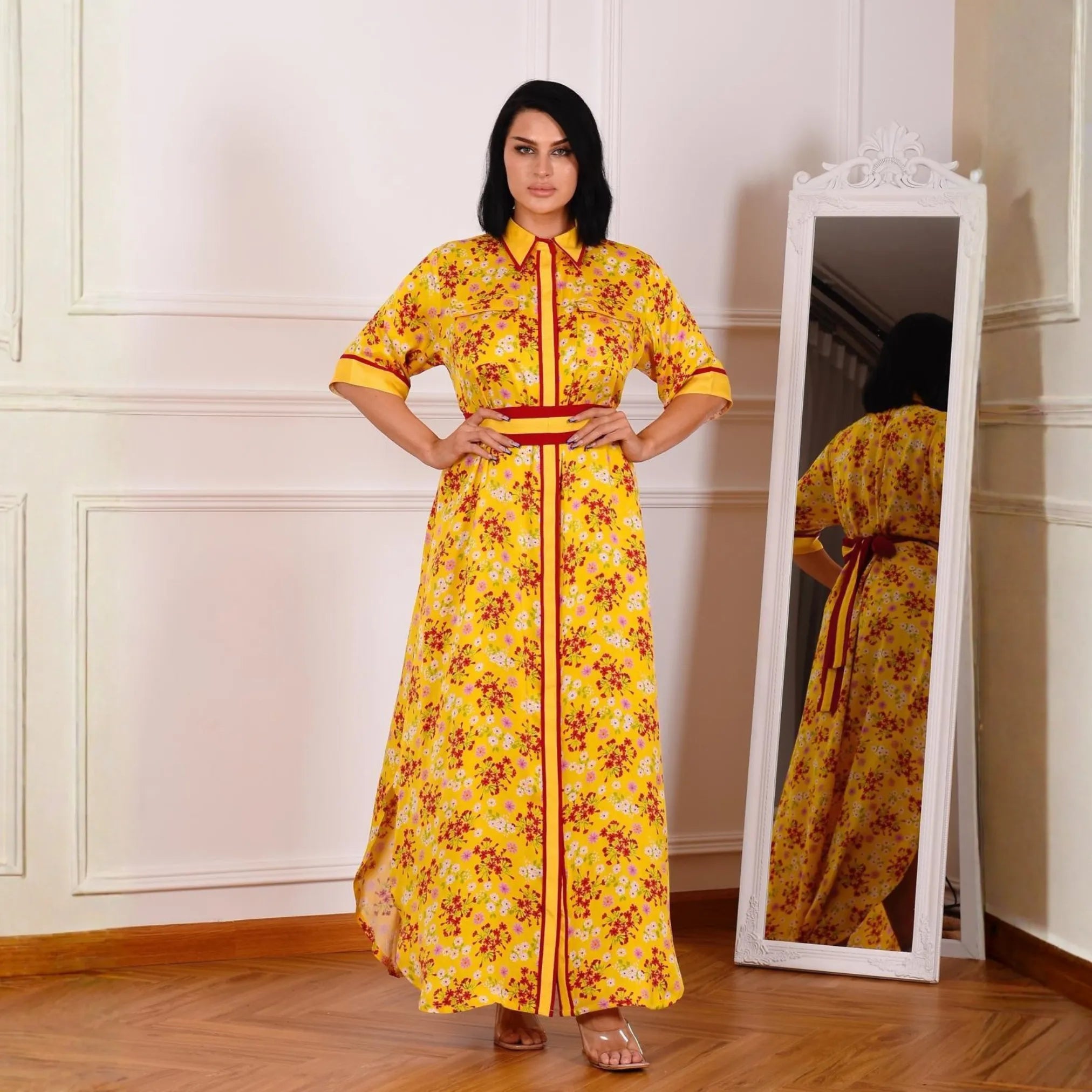 Woman in a yellow floral dress standing next to a full-length mirror.