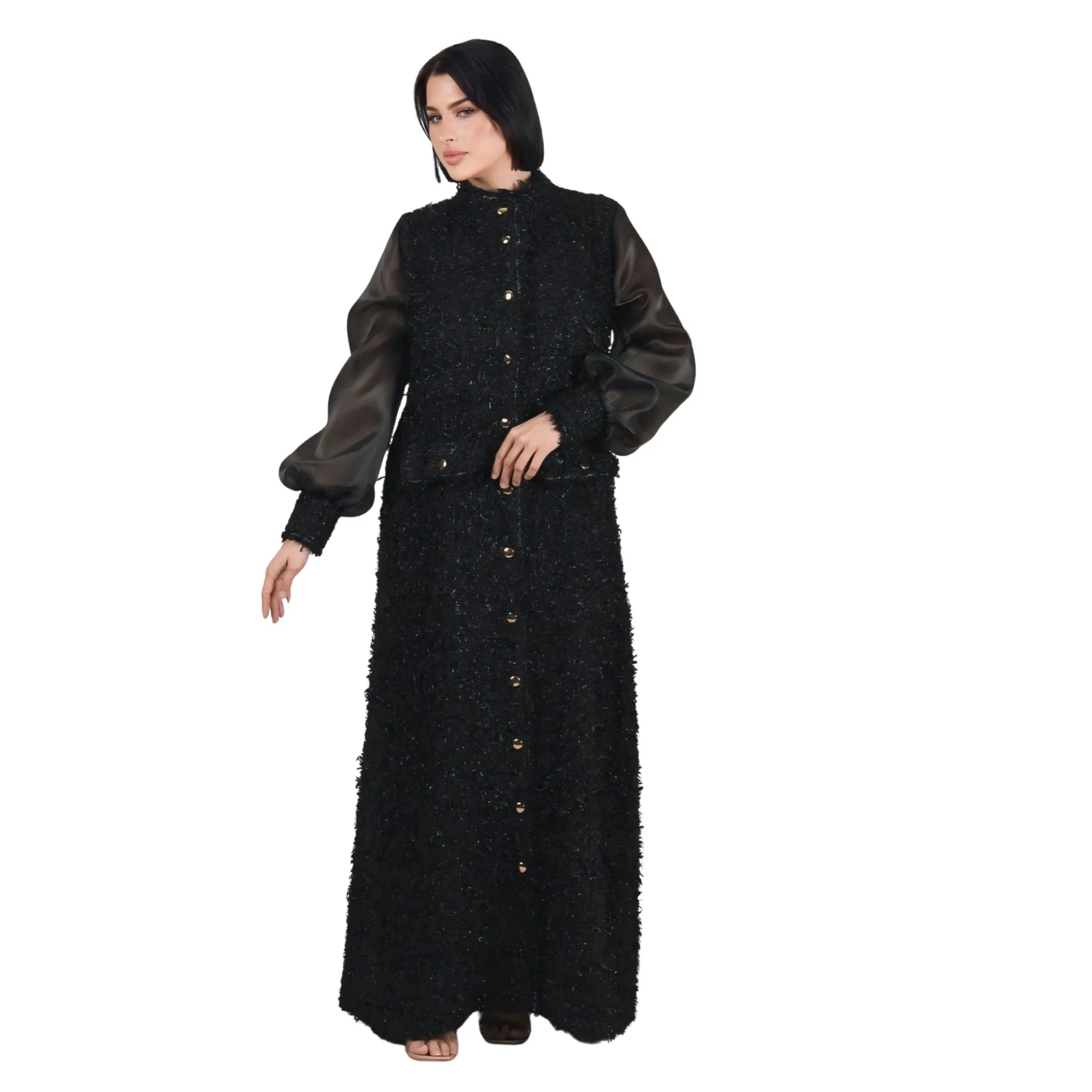Woman wearing a black textured dress with a long coat on a white background