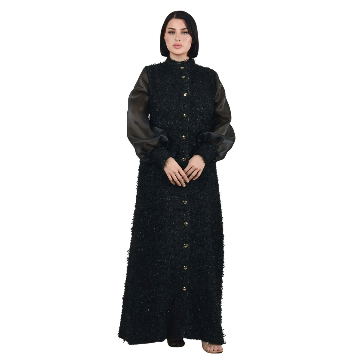 Woman wearing a black textured dress with sheer sleeves on a white background