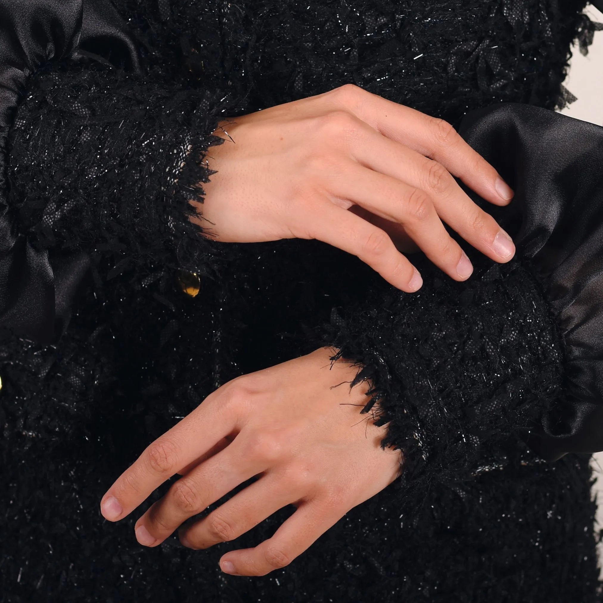 Close-up of hands wearing black textured gloves against a dark background
