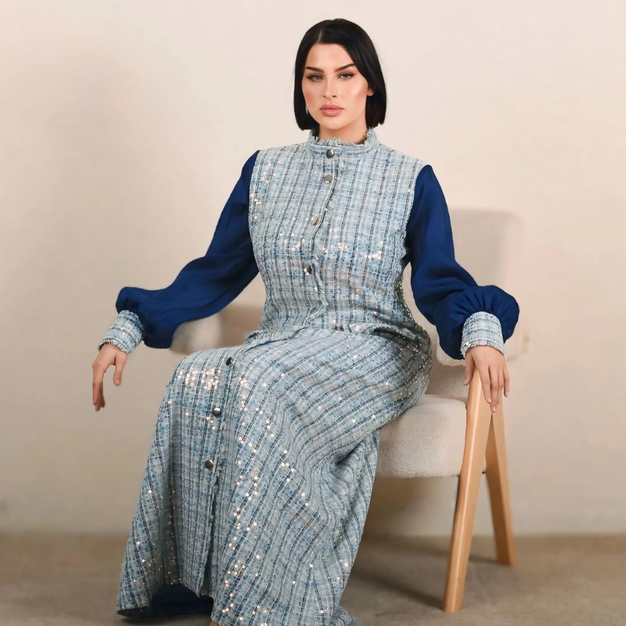 Woman sitting on a chair wearing a blue and gray patterned outfit.