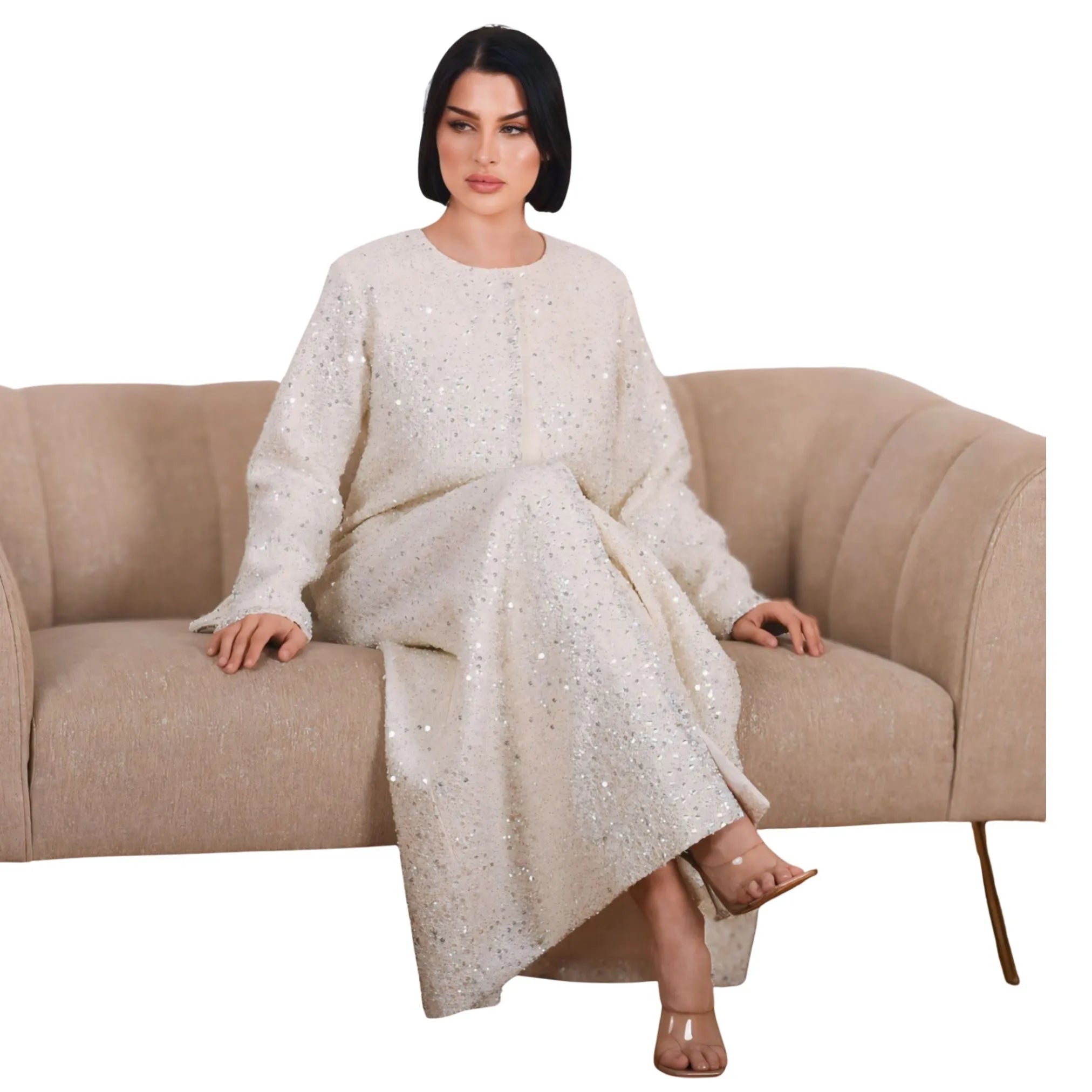 Woman in a white dress sitting on a beige couch against a white background