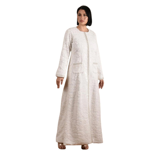 Woman wearing a long, light-colored dress with a textured pattern on a white background