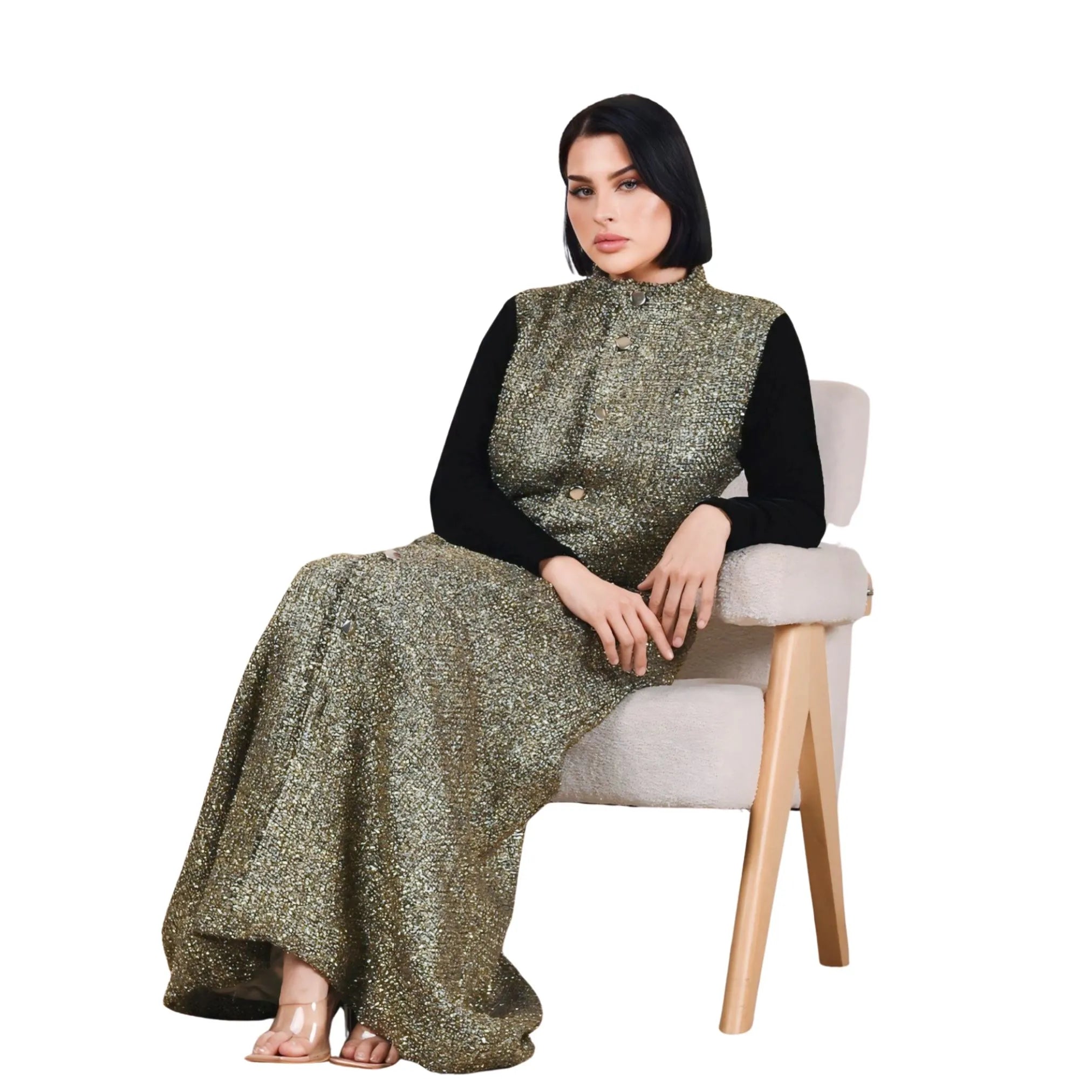 Woman wearing a long, patterned dress sitting on a chair against a white background