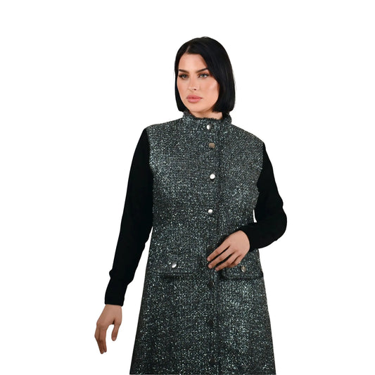 Woman wearing a black and gray patterned vest over a black long-sleeve shirt on a white background