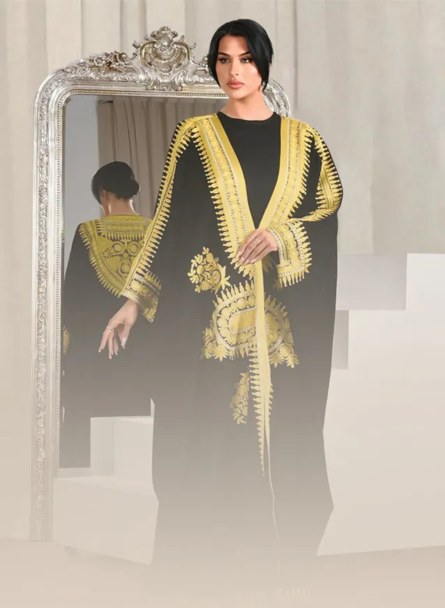 Woman wearing a black and gold embroidered dress in front of a mirror.