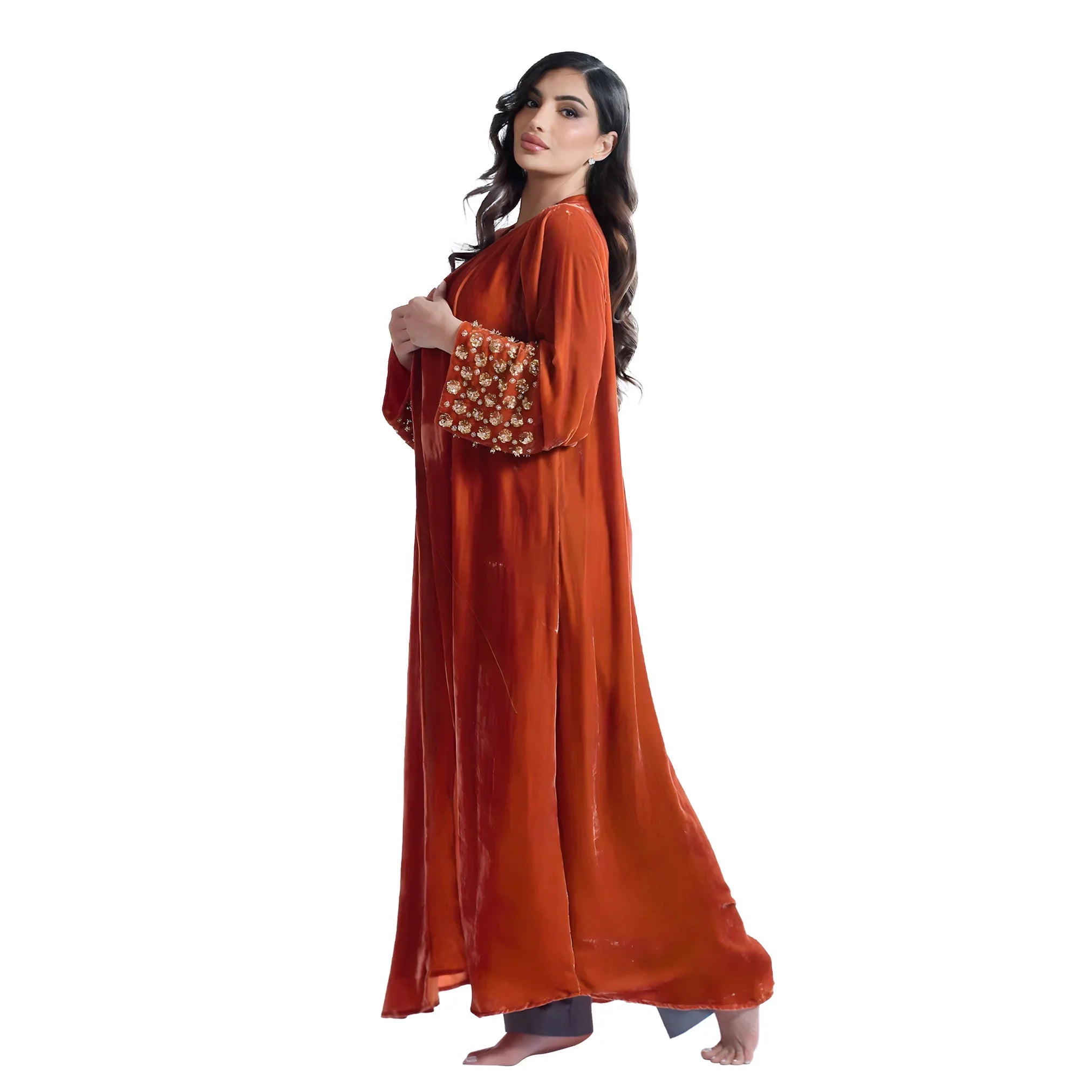 Woman wearing a long orange dress abaya with floral embellishments on a white background