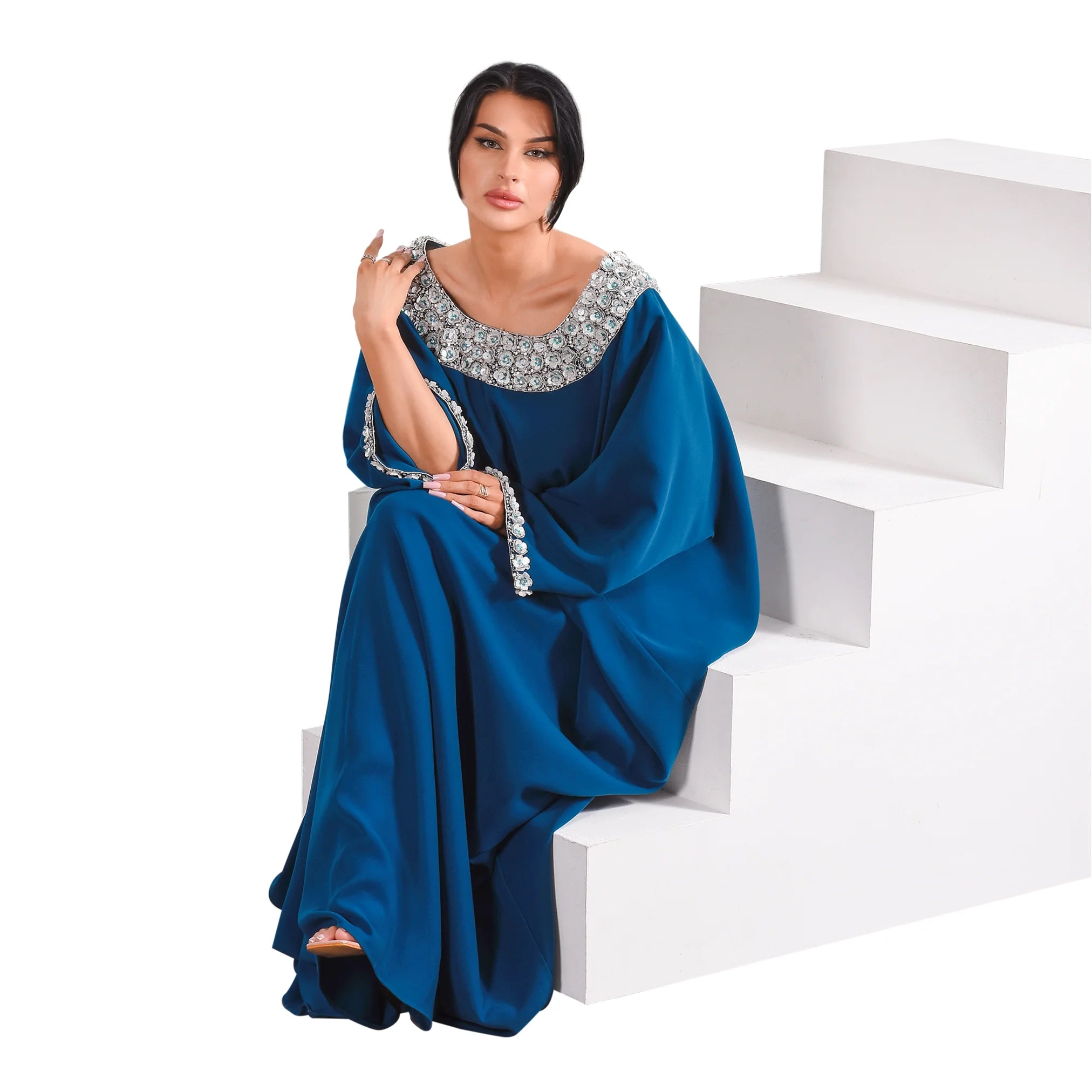 Woman wearing a blue evening jalabiya with a white background