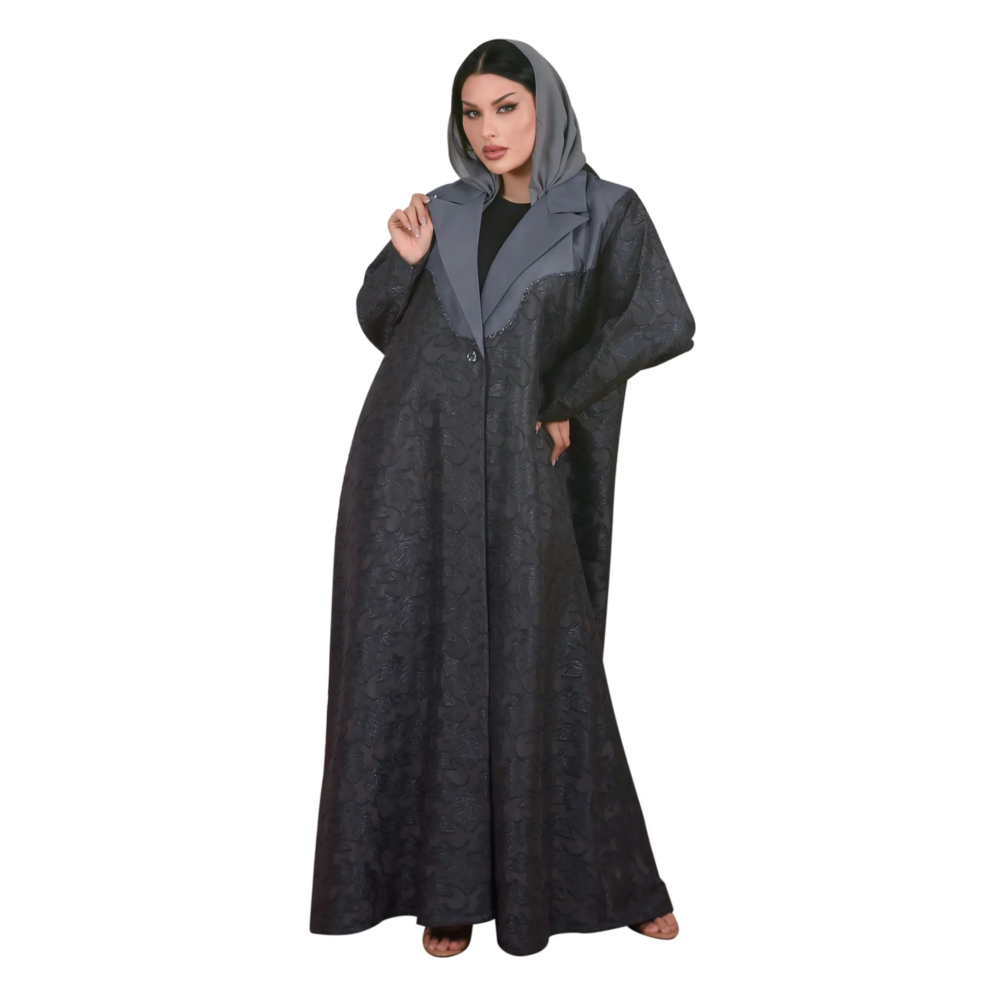 Woman wearing a long, dark gray abaya with a hood on a white background