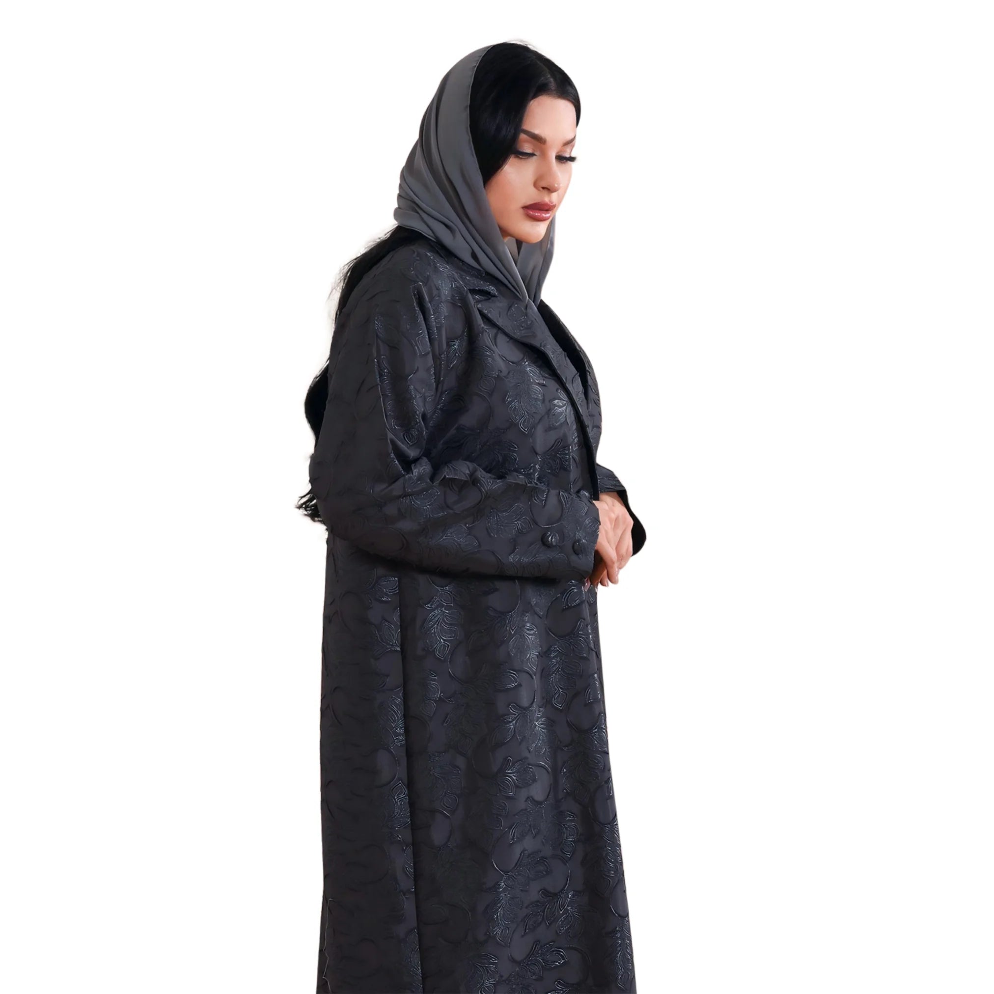 Woman wearing a long dark abaya with a hood on a white background